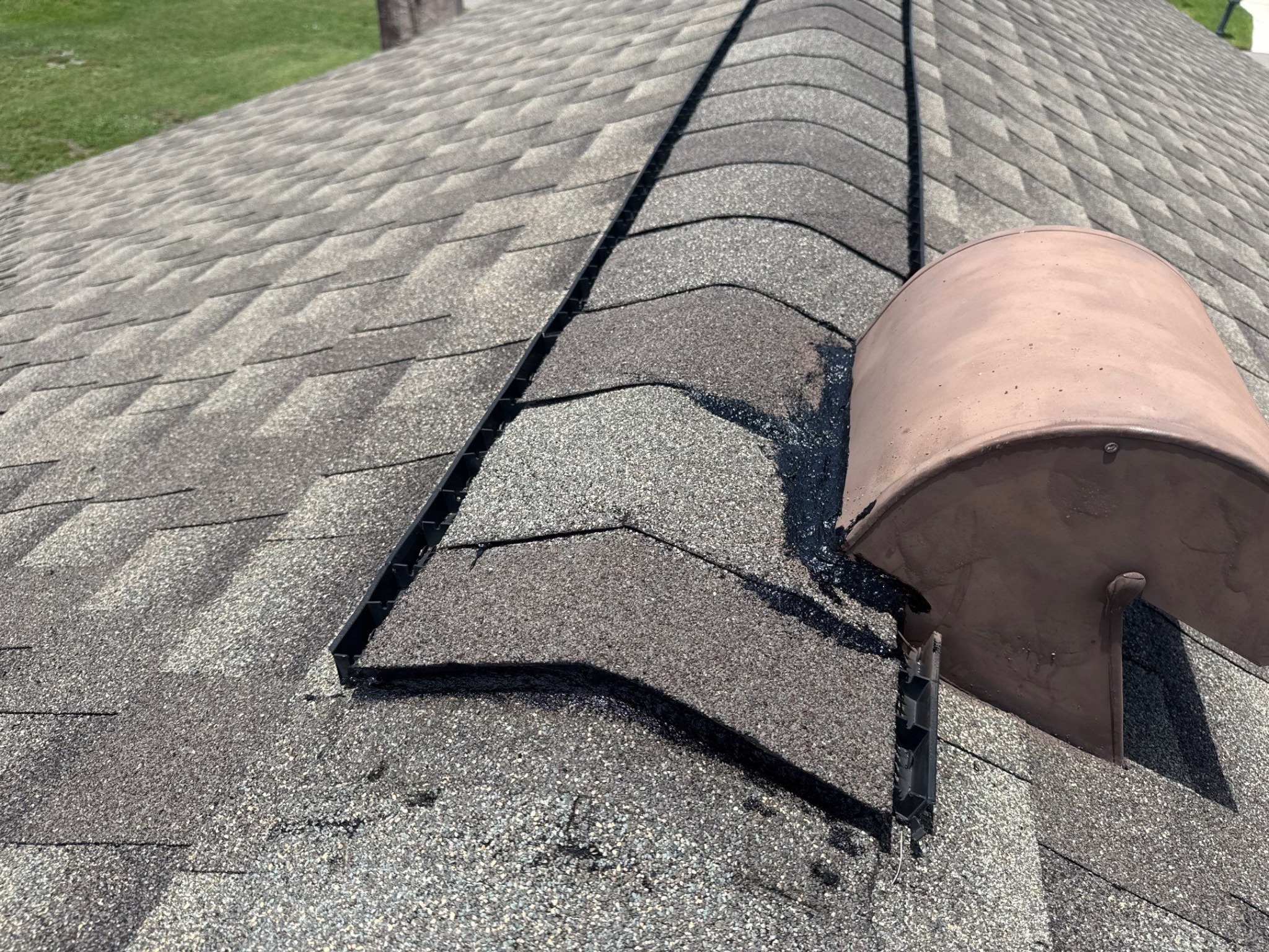 Close view of ridge cap shingles meeting a ridge vent on an asphalt shingle roof