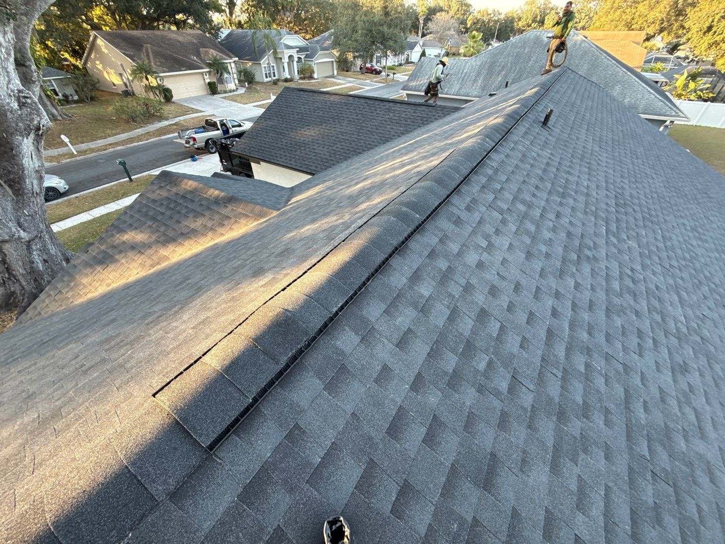 New asphalt shingle roof showing a hip line with ridge cap shingles and straight, even courses