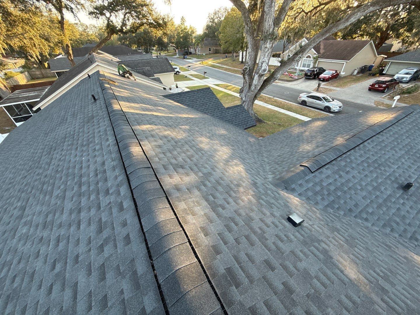 Newly installed shingle roof viewed along the ridge, showing straight shingle courses and a finished ridge cap