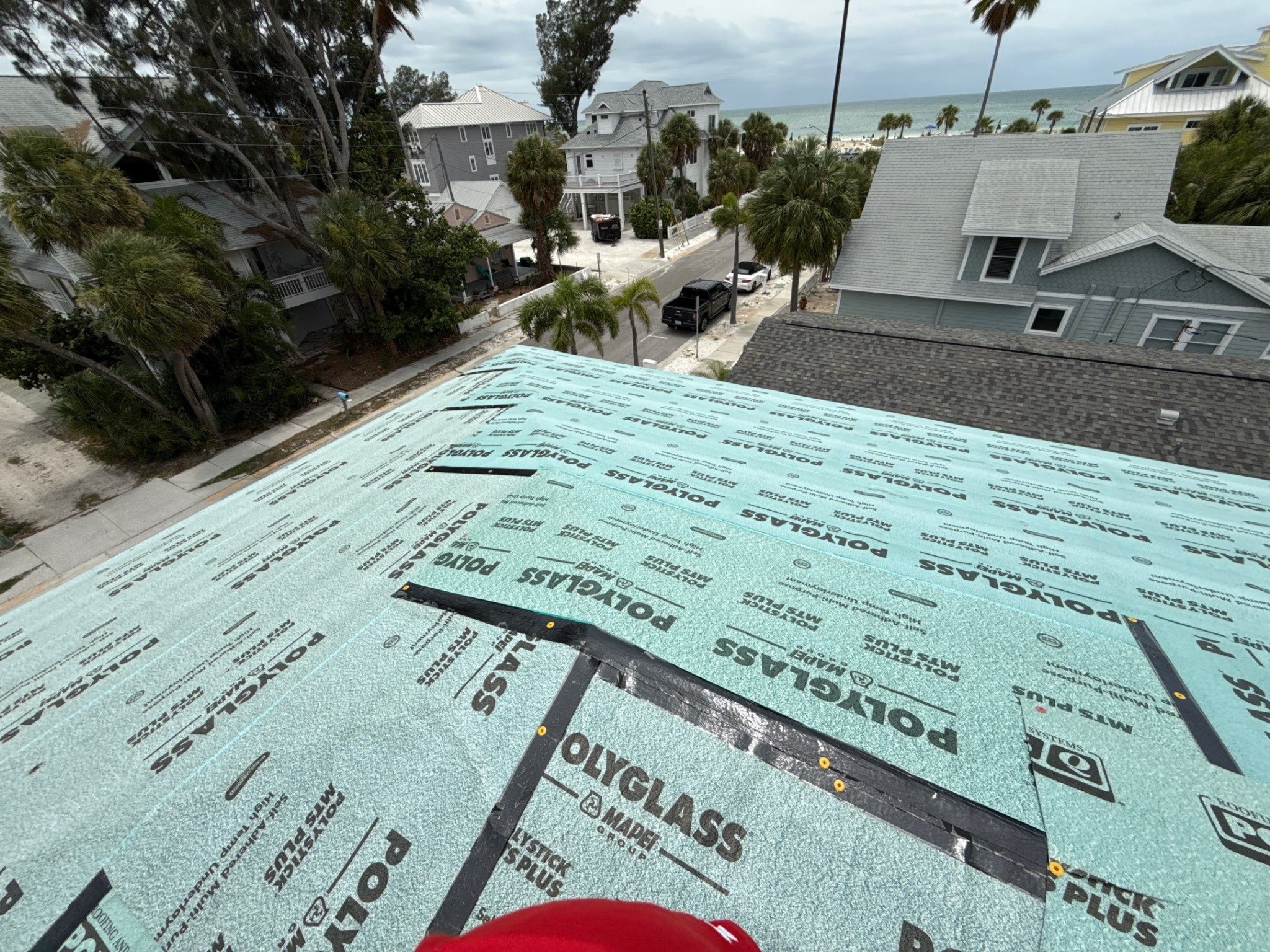 Roof deck fully covered with teal synthetic underlayment on a home before final roofing is installed
