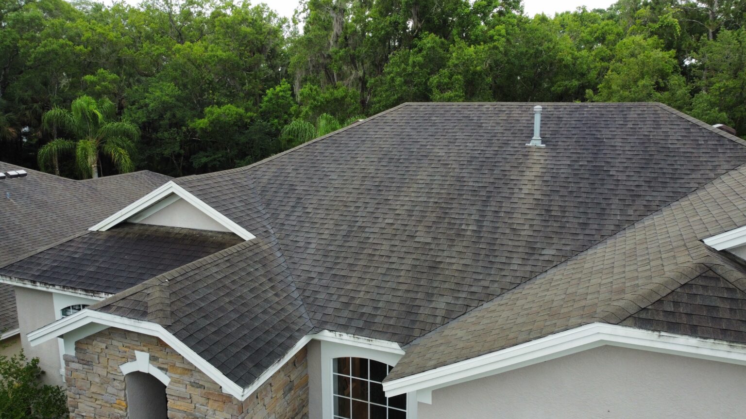 Aerial view of an aged asphalt shingle roof with surface discoloration and streaking